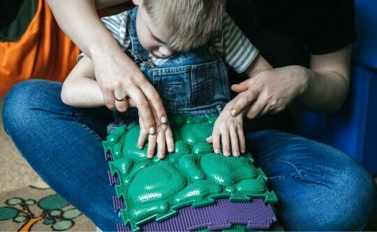 A child with blindness learning tactile touch and feeling of the toy on their lap