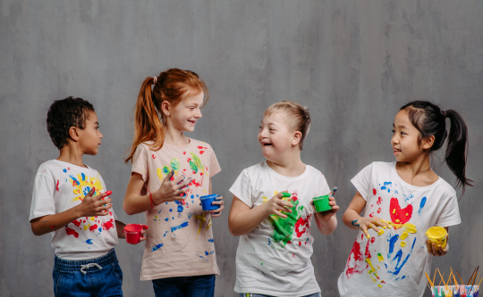 children with diverse abilities finger painting and laughing.